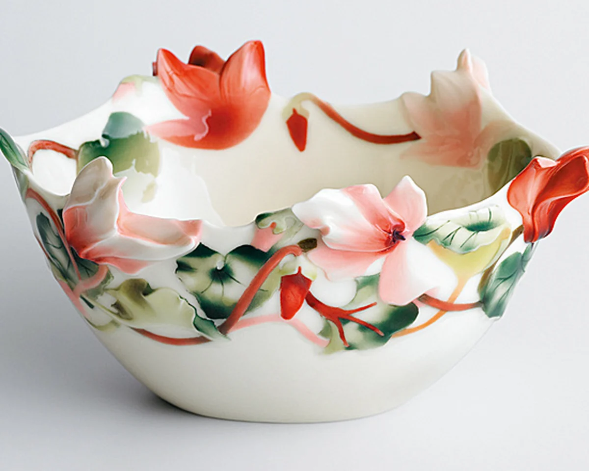 White porcelain bowl with a scalloped rim and sculpted red and pink cyclamen flowers
