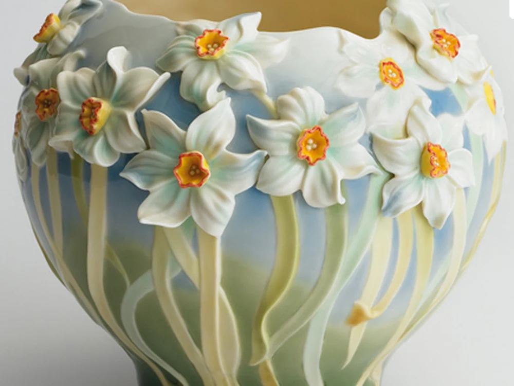 Rounded porcelain vase with a wreath of sculpted white narcissus over a blue-green ground